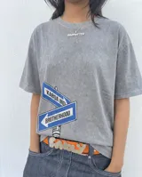 Remera de corte oversize color gris con efecto stone wash, con estampa frontal de carteles de señalización vial con la inscripción 'KABOA IND' y 'BROTHERHOOD'.