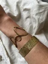 Pulsera brazalete rígido de alpaca plateada con textura irregular hecha a mano.