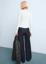 Jeans tiro alto wide leg con diseño de cinco bolsillos y cierre frontal de cremallera y botón.