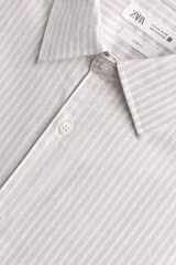 Camisa slim fit de algodón, color beige con rayas verticales blancas. Presenta cuello italiano, manga larga con puño de botón y cierre frontal de botonadura.