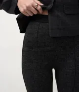 Pantalón tipo legging de tiro alto confeccionado en punto roma, con textura sutil y costuras frontales tipo nervura que estilizan la silueta.