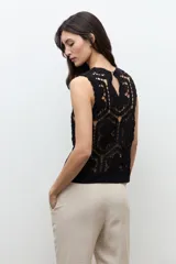Top sin mangas confeccionado en tejido de crochet con patrón geométrico y floral, en color beige claro.