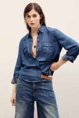 Camisa de denim gris oscuro efecto acid wash, de manga larga, con bolsillos frontales con solapa y broches metálicos a presión.