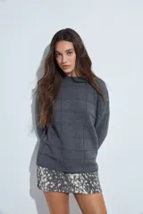 Sweater de punto gris con cuello a la base y diseño de trama geométrica en relieve. Presenta un calce relajado con mangas largas y puños tejidos.