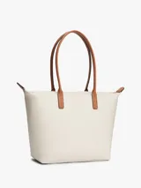 Cartera tote Tommy Hilfiger de nailon color beige, con dos asas superiores de cuero sintético tostado y cierre de cremallera. Presenta el monograma metálico TH en la parte delantera.
