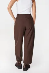 Pantalón de corte sastrero color marrón, con diseño de pinzas en la cintura, cierre frontal con botón y corte recto holgado.