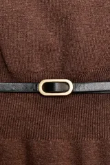 Jersey de punto color marrón, con cuello barco y mangas anchas estilo capa. La cintura está entallada y marcada con un cinturón fino negro con hebilla ovalada.