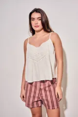 Blusa color off white de algodón peinado, sin mangas, con tirantes finos, escote en V con detalles de encaje y bordados, y pliegues decorativos en los laterales.
