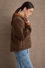 Campera corta de paño color marrón con detalles en cuero sintético al tono en cuello, puños y solapas de bolsillos. Presenta cierre frontal con botones metálicos dorados y dos bolsillos frontales tipo cargo.