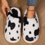 Pantuflas sin talón de peluche suave con estampado de manchas de vaca en tonos blanco y marrón, con suela de goma antideslizante.