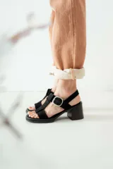 Sandalias de gamuza negra con taco cuadrado y plataforma. Presentan un diseño de tiras anchas con una hebilla metálica plateada ajustable en el lateral.