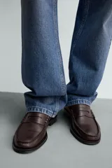 Mocasín de vestir fabricado en piel color marrón oscuro, con detalle de antifaz en el empeine, plantilla de piel y suela a contraste con ligero tacón.