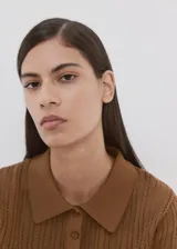 Chaleco de punto fino de algodón con diseño calado, cuello polo, manga corta y cierre frontal con tres botones.