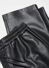 Pantalón de cuero sintético negro, de corte recto, largo y tiro medio. Presenta cintura elástica con cordón ajustable y bolsillos laterales.