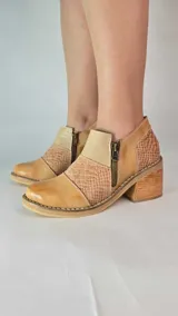 Botinetas de cuero color tostado con diseño de paneles texturizados tipo reptil, taco cuadrado de madera y cierre lateral con cremallera.