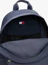 Mochila de diseño redondeado en color azul, confeccionada en poliéster. Cuenta con un compartimento principal con cierre de cremallera, un bolsillo exterior frontal con cierre, asa superior y correas acolchadas ajustables. Incluye parche distintivo de Tommy Jeans en la parte delantera.