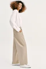 Pantalón barrel color azul marino, de tiro bajo, pernera holgada con diseño redondeado que se estrecha hacia el tobillo, con bolsillos delanteros y cierre frontal.