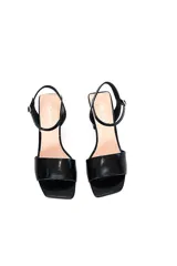 Sandalias de cuero vacuno en charol negro, con taco bloque de altura media, tira frontal ancha y tira ajustable al tobillo con hebilla metálica.
