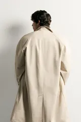 Trench relaxed fit de algodón color beige, con cuello solapa, manga larga y cierre frontal de botonadura oculta por solapa. Presenta bolsillos de vivo en la cadera y abertura en el centro de la espalda.