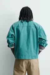 Cazadora boxy fit de algodón con efecto lavado, color verde, cuello de pana marrón a contraste y grandes bolsillos con solapa en la parte delantera. Presenta cierre frontal con alamares metálicos.