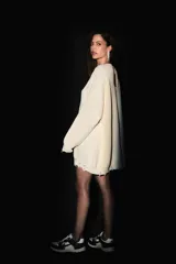 Sweater oversized color crema, tejido de punto con escote en V, roturas en ruedo y puños, y badana de PU en la espalda.