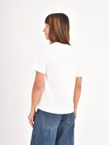 Remera color gris topo con estampa frontal en blanco que incluye gráficos de llaveros y la inscripción "Lucky Charm".