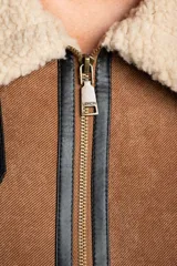 Chaleco estilo gamulán de color negro, con interior y cuello de corderito sintético. Presenta cierre frontal, detalles en cuero sintético y corte oversize.