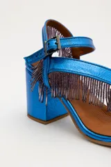 Sandalias de cuero gamuzado color azul, con taco ancho y tiras cruzadas en el empeine decoradas con flecos de cuentas. Cuentan con pulsera regulable al tobillo con hebilla metálica.