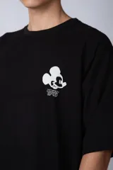 Remera negra de corte oversize confeccionada en algodón pesado, con estampa pequeña de Mickey Mouse en el pecho y diseño gráfico en la espalda.