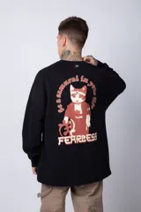 Buzo de tejido friza color crema, de corte oversize y cuello redondo. Presenta un pequeño bordado o parche en el pecho izquierdo con un diseño de cabeza de animal en tonos rojizos/terracota.