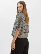 Camisa de corte holgado y silueta recta con estampado geométrico bicolor de eslabones. Presenta cuello camisero clásico, mangas cortas amplias y cierre frontal con botones y vivos a contratono.