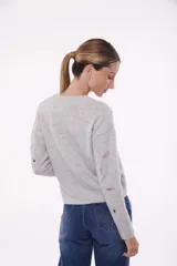 Sweater verde claro con bordado de flores pequeñas.