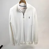 Buzo de punto color crudo, con medio cierre frontal y cuello alto.