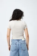 Remera blanca de punto acanalado con escote en V fruncido y puntilla en el borde.