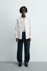 Camisa de manga larga, color blanco, con cuello italiano y corte slim fit. Presenta cierre frontal de botonadura y puños con botón.