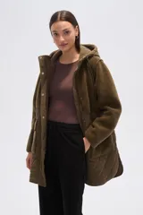 Campera de diseño híbrido en color verde oliva, que combina paneles de corderito en la parte superior y capucha con una sección inferior acolchada con diseño de rombos. Cuenta con cierre frontal, botones a presión y bolsillos frontales con solapa.