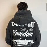 Canguro con capucha de corte oversize y efecto lavado, color gris oscuro. Presenta un estampado pequeño en el pecho con el dibujo de un auto y la inscripción 'EST. VCP 2015'. Cuenta con bolsillo frontal tipo canguro y etiqueta pequeña en el puño.