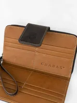 Billetera grande de cuero con estampado animal print tipo leopardo y detalles en cuero marrón. Cuenta con una correa de muñeca incorporada y cierre con solapa y broche grabado.