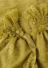 Top amarillo de encaje sin mangas, con cuello gorguera alto y cierre de botones en el cuello. Cuenta con forro interior y diseño entallado.