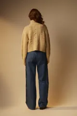 Sweater tejido color crema con cuello alto y cierre metálico frontal parcial.