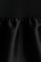Vestido corto de punto con escote redondo y mangas cortas. Presenta un diseño entallado en el cuerpo y una falda con volado inferior confeccionado en tela satinada con brillo.