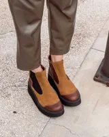 Botinetas de caña baja con diseño bicolor en tonos marrón y suela de plataforma negra. Presentan una combinación de gamuza y cuero, con paneles elásticos laterales y puntera reforzada.