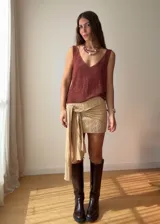 Mini falda de tejido de punto con textura en zigzag, color beige dorado. Presenta un diseño ajustado con un lazo lateral integrado que cae sobre la pierna.