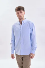 Camisa de manga larga confeccionada en tejido oxford color celeste, con cuello abotonado, cierre frontal de botones y bolsillo en el pecho.