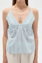 Musculosa blanca de algodón con diseño de broderie, escote en V, tirantes finos regulables y corte holgado.