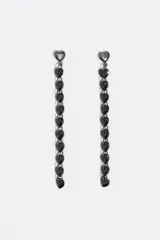 Caravanas largas de color negro con diseño de corazones en cascada. Presentan una serie de cristales facetados en forma de corazón engarzados en una estructura de acero inoxidable con acabado metálico oscuro y cierre a presión.