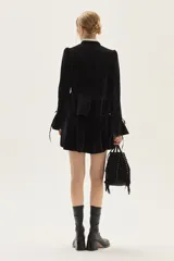 Cartera tipo bandolera de cuero gamuzado color marrón, con diseño de flecos laterales y detalle de tachas metálicas. Cuenta con cierre de cordón ajustable con borlas y correa regulable.