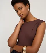 Body color terracota, de manga corta con pliegues en los hombros y escote canoa. Corte ajustado al cuerpo con broches inferiores.