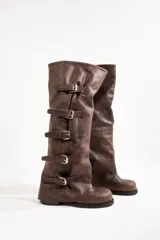 Botas altas de cuero color marrón con múltiples correas con hebillas plateadas.