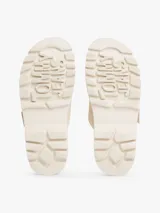 Sandalias planas de color blanco hueso con dos tiras ajustables mediante hebillas metálicas. Cuentan con una suela gruesa y dentada de plataforma.